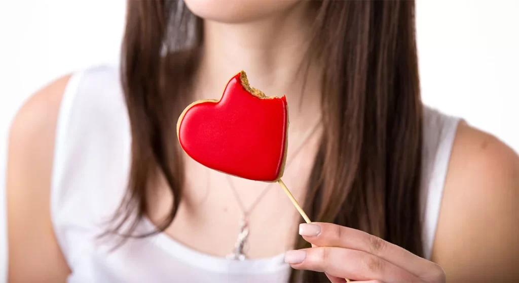 mujer con galleta de corazón mordida